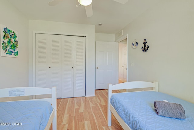 bedroom with light wood-style floors, a closet, and a ceiling fan