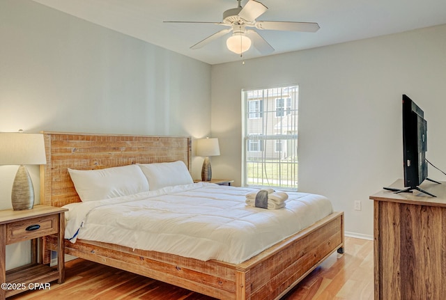 bedroom with light wood-style flooring, baseboards, and ceiling fan