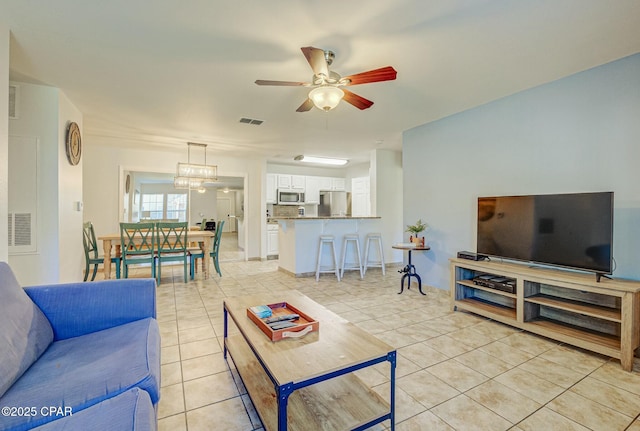 living area with a ceiling fan and light tile patterned floors