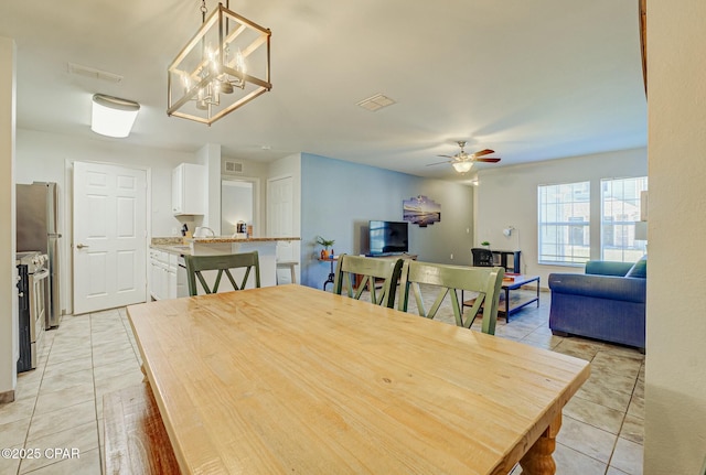dining room with light tile patterned floors, a ceiling fan, and a chandelier