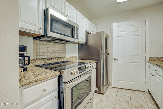 kitchen with appliances with stainless steel finishes, backsplash, white cabinetry, light tile patterned floors, and light stone counters