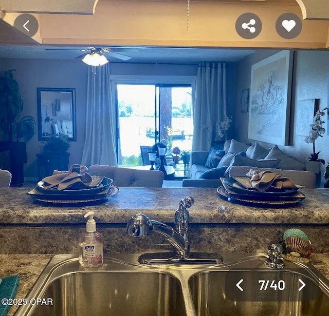 kitchen featuring a ceiling fan, dark countertops, and a sink