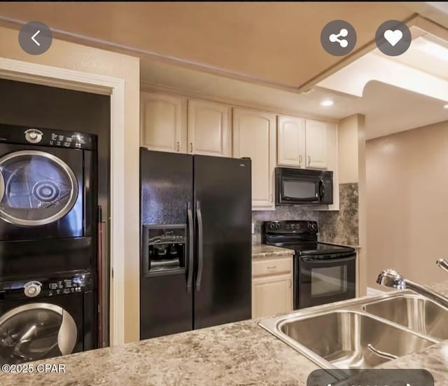 kitchen with backsplash, stacked washer / dryer, white cabinets, a sink, and black appliances