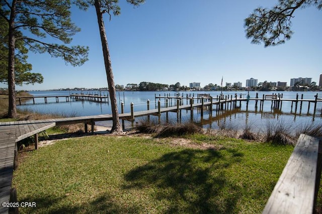 view of dock featuring a lawn, a water view, and a city view