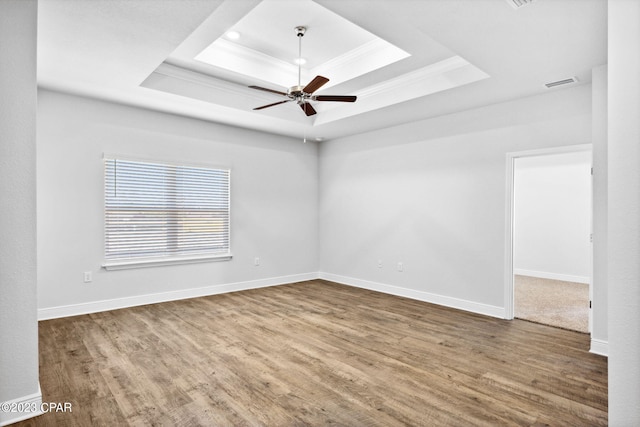 spare room featuring visible vents, crown molding, wood finished floors, a raised ceiling, and a ceiling fan