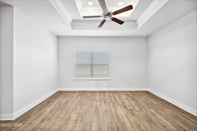 unfurnished room with crown molding, a raised ceiling, and baseboards