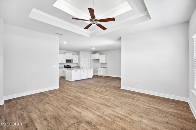 unfurnished living room with visible vents, a raised ceiling, baseboards, and ornamental molding