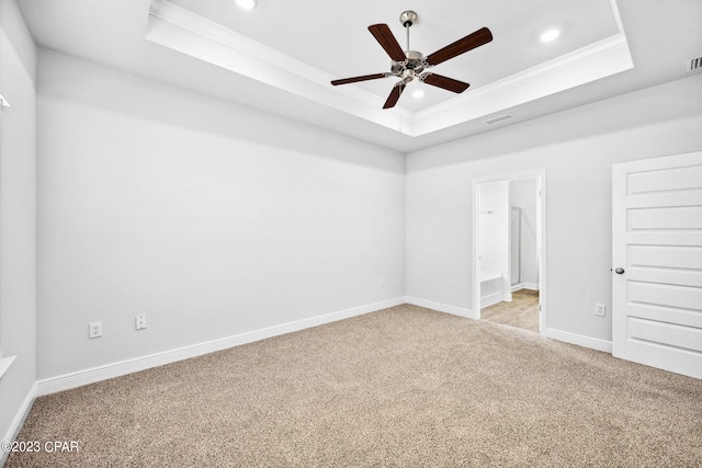 spare room with a tray ceiling, light colored carpet, and ornamental molding