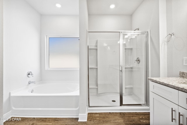 bathroom with a bath, a shower stall, vanity, and wood finished floors