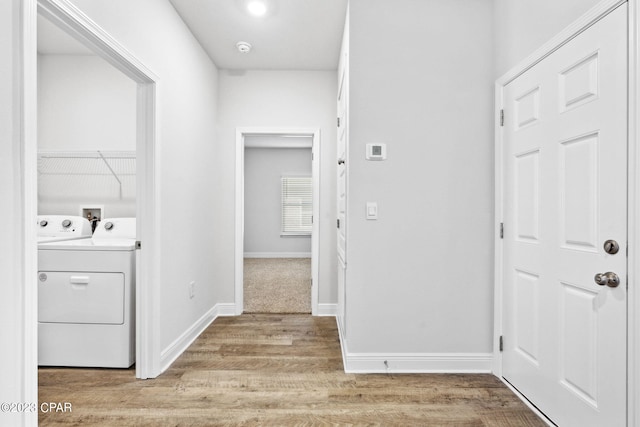 corridor with baseboards, washing machine and dryer, and light wood-style flooring