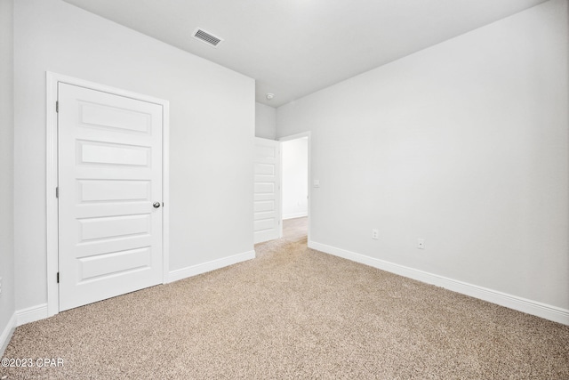 unfurnished bedroom featuring visible vents, light colored carpet, and baseboards