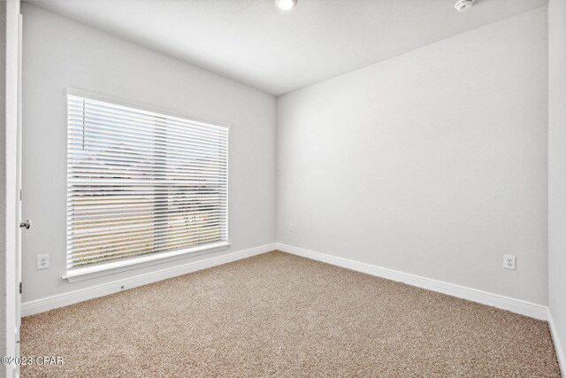 unfurnished room featuring carpet and baseboards