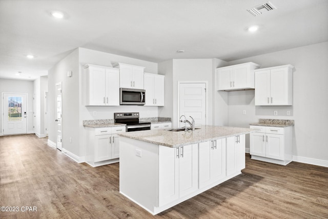 kitchen featuring visible vents, a sink, wood finished floors, white cabinetry, and stainless steel appliances