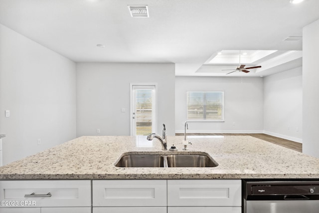 kitchen with visible vents, white cabinetry, a tray ceiling, a sink, and dishwasher