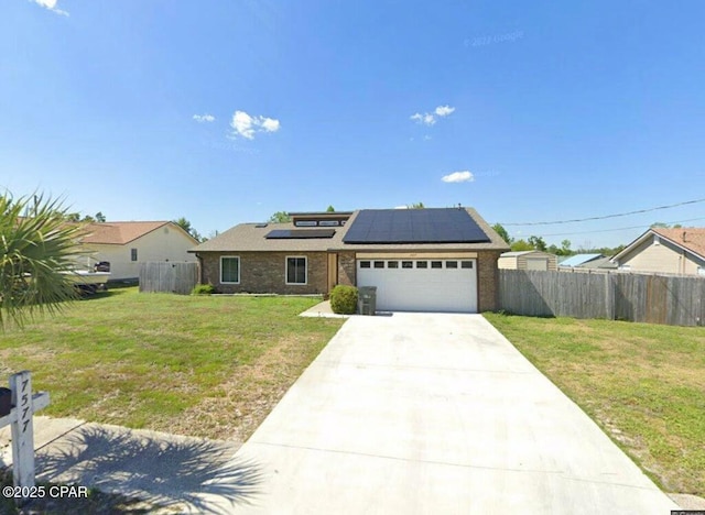 single story home with a garage, fence, concrete driveway, roof mounted solar panels, and a front yard