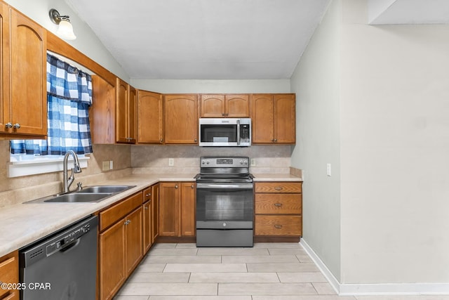 7577 Kelsey Dr, Panama City, FL 32404 - kitchen featuring brown cabinets, stainless steel appliances, light countertops, decorative backsplash, and a sink
