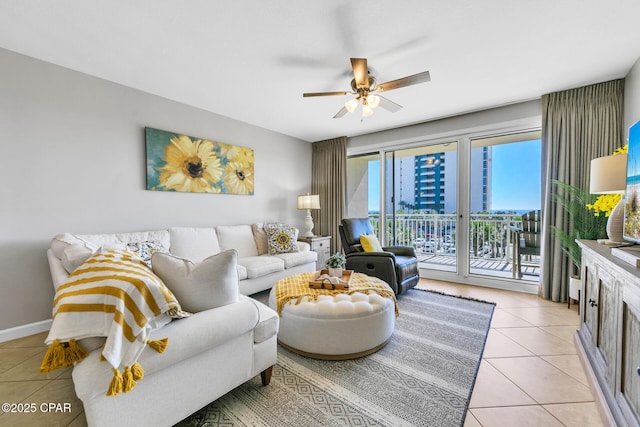 living room featuring light tile patterned floors, ceiling fan, baseboards, and a city view