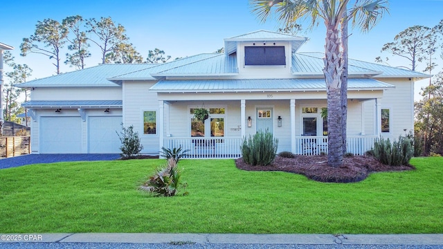 view of front facade featuring covered porch, aphalt driveway, metal roof, and a front lawn