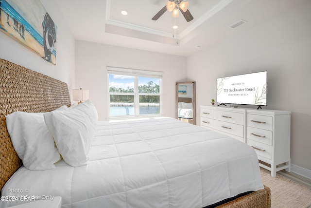 bedroom with a tray ceiling, light wood finished floors, recessed lighting, visible vents, and ornamental molding