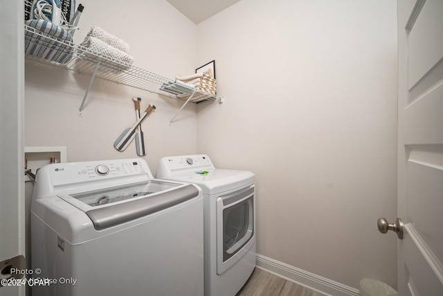 washroom with wood finished floors, laundry area, baseboards, and separate washer and dryer