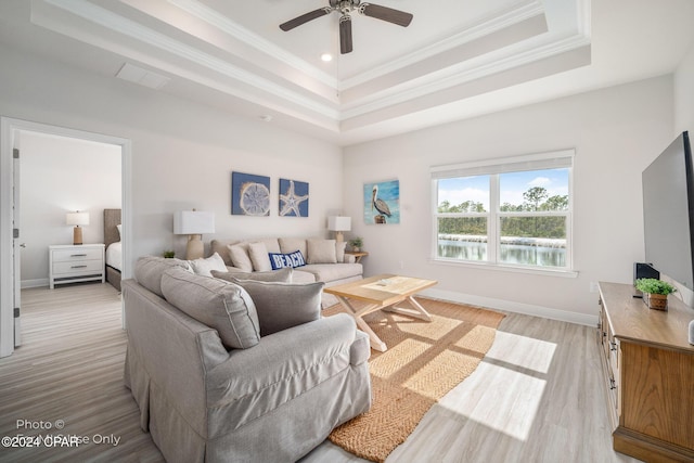 living room featuring a tray ceiling, crown molding, visible vents, light wood-type flooring, and baseboards