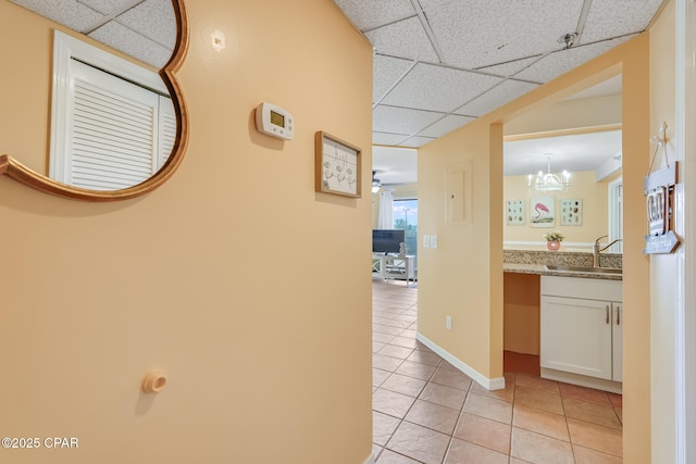 8730 Thomas Dr Unit 1201-B, Panama City Beach, FL 32408 - hallway with a notable chandelier, a sink, a drop ceiling, light tile patterned floors, and baseboards