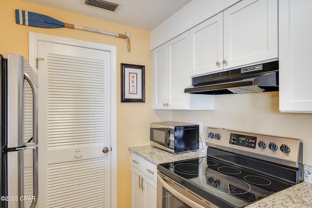 8730 Thomas Dr Unit 1201-B, Panama City Beach, FL 32408 - kitchen featuring light stone counters, visible vents, stainless steel appliances, under cabinet range hood, and white cabinetry