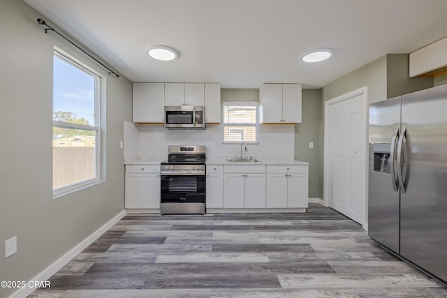 1705 Lake Ave, Panama City, FL 32401 - kitchen with appliances with stainless steel finishes, a sink, white cabinetry, and light wood finished floors