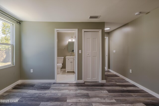 1705 Lake Ave, Panama City, FL 32401 - unfurnished bedroom featuring dark wood-style flooring, connected bathroom, a sink, baseboards, and a closet
