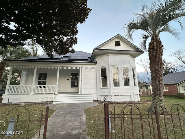 view of front of house featuring solar panels, crawl space, fence private yard, covered porch, and a front yard