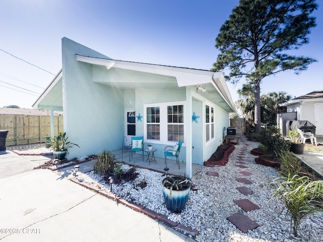 exterior space featuring a patio area, fence, central AC unit, and stucco siding