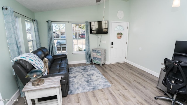 living area with lofted ceiling, a textured ceiling, wood finished floors, and baseboards