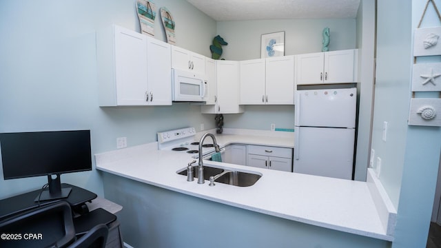 kitchen featuring white appliances, white cabinets, a peninsula, light countertops, and a sink