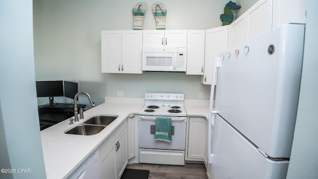 kitchen featuring light stone counters, white appliances, wood finished floors, a sink, and white cabinetry