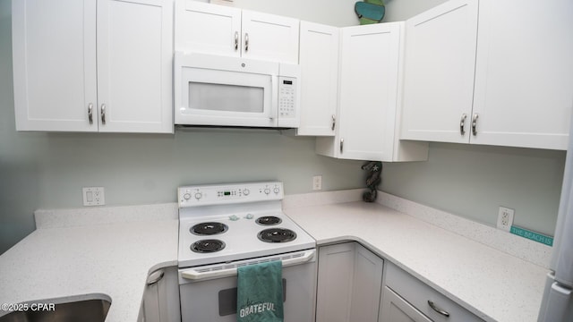 kitchen with white appliances, white cabinetry, and light stone counters