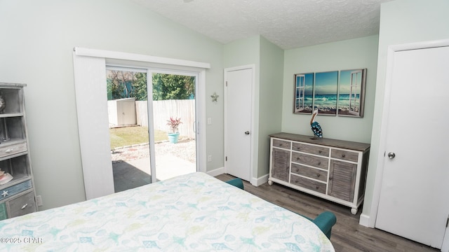 bedroom featuring baseboards, dark wood finished floors, lofted ceiling, access to exterior, and a textured ceiling