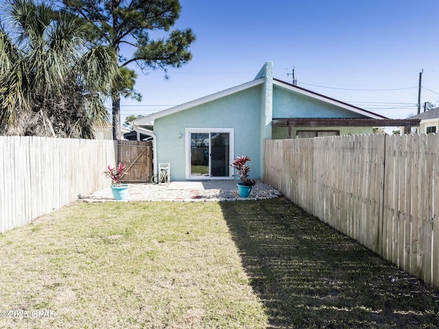 rear view of house with a yard, a fenced backyard, and stucco siding