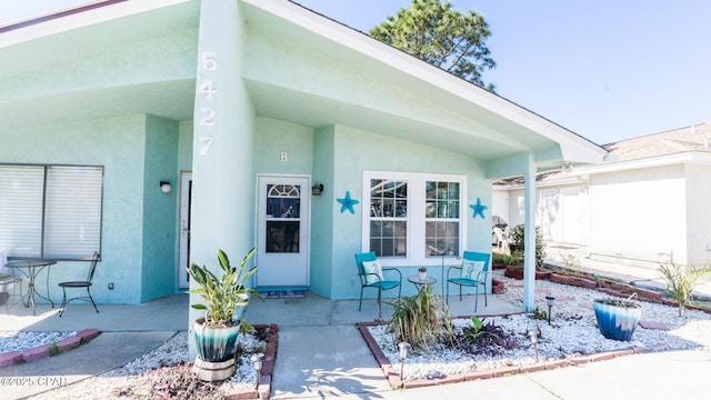 view of exterior entry with a patio area and stucco siding