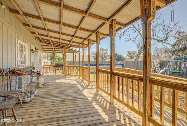 wooden terrace with a playground and fence