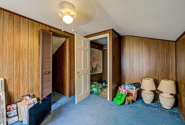 carpeted bedroom with lofted ceiling, a closet, wooden walls, and a ceiling fan