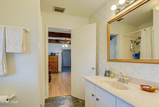 bathroom featuring beamed ceiling, vanity, visible vents, and wallpapered walls