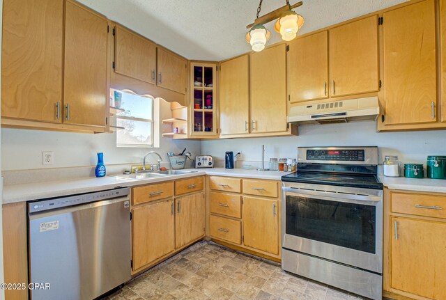 kitchen with stainless steel appliances, light countertops, a sink, a textured ceiling, and under cabinet range hood