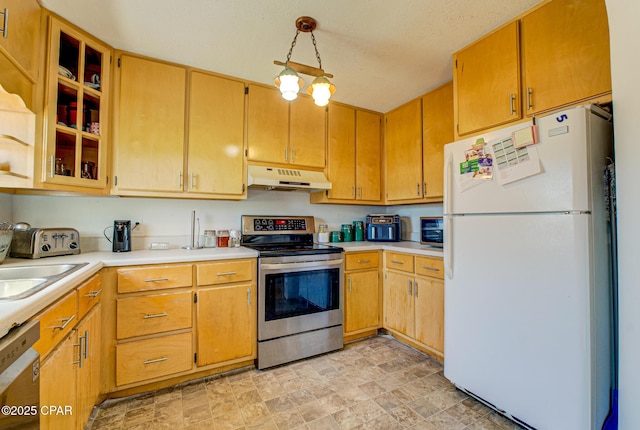 kitchen with glass insert cabinets, stone finish flooring, stainless steel appliances, light countertops, and under cabinet range hood