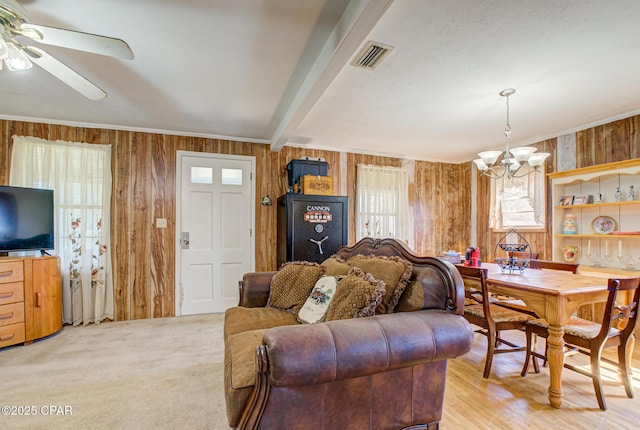 living area featuring wooden walls, visible vents, beamed ceiling, and ornamental molding