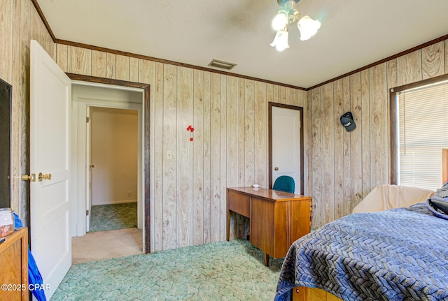 bedroom with carpet, wooden walls, visible vents, and crown molding