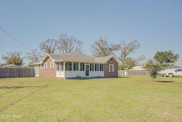 view of front of house featuring a sunroom, fence, a front lawn, and brick siding