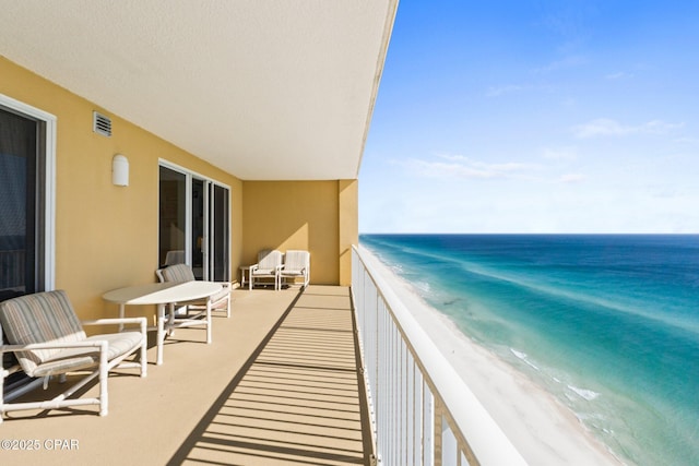 balcony featuring a beach view, visible vents, and a water view