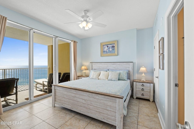 bedroom with light tile patterned flooring, ceiling fan, access to exterior, a water view, and a textured ceiling