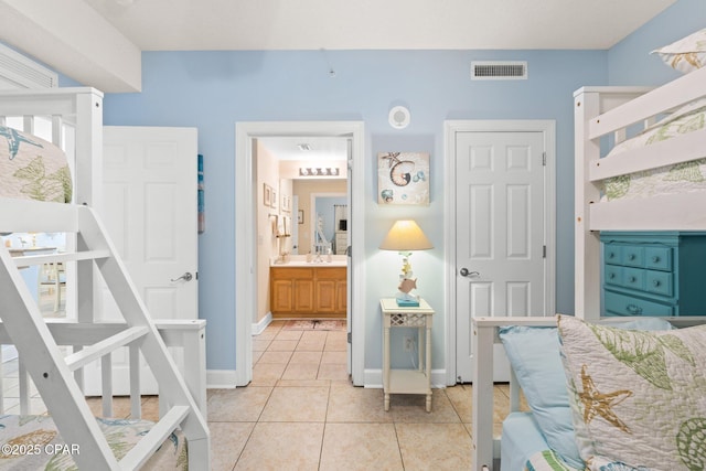 bedroom with light tile patterned flooring, visible vents, baseboards, and a sink