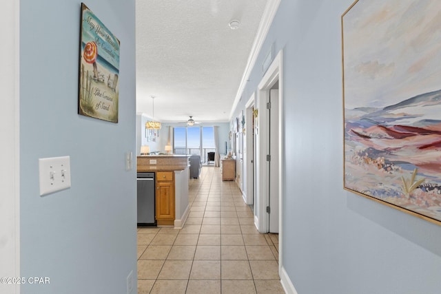 hall with light tile patterned flooring, a textured ceiling, and baseboards